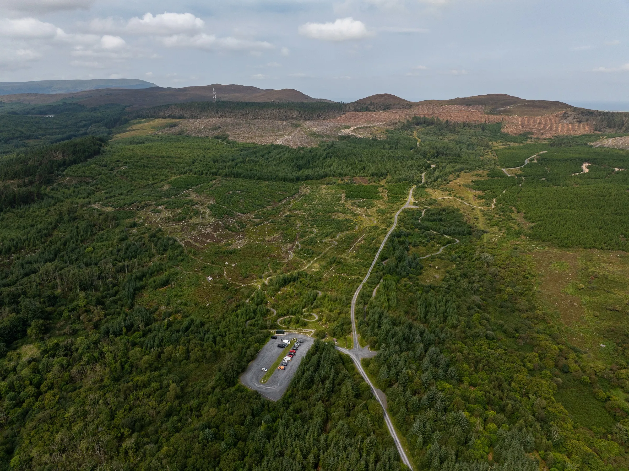 Aerial view of a car park and winding bike trails through a vast green forest in County Sligo.
