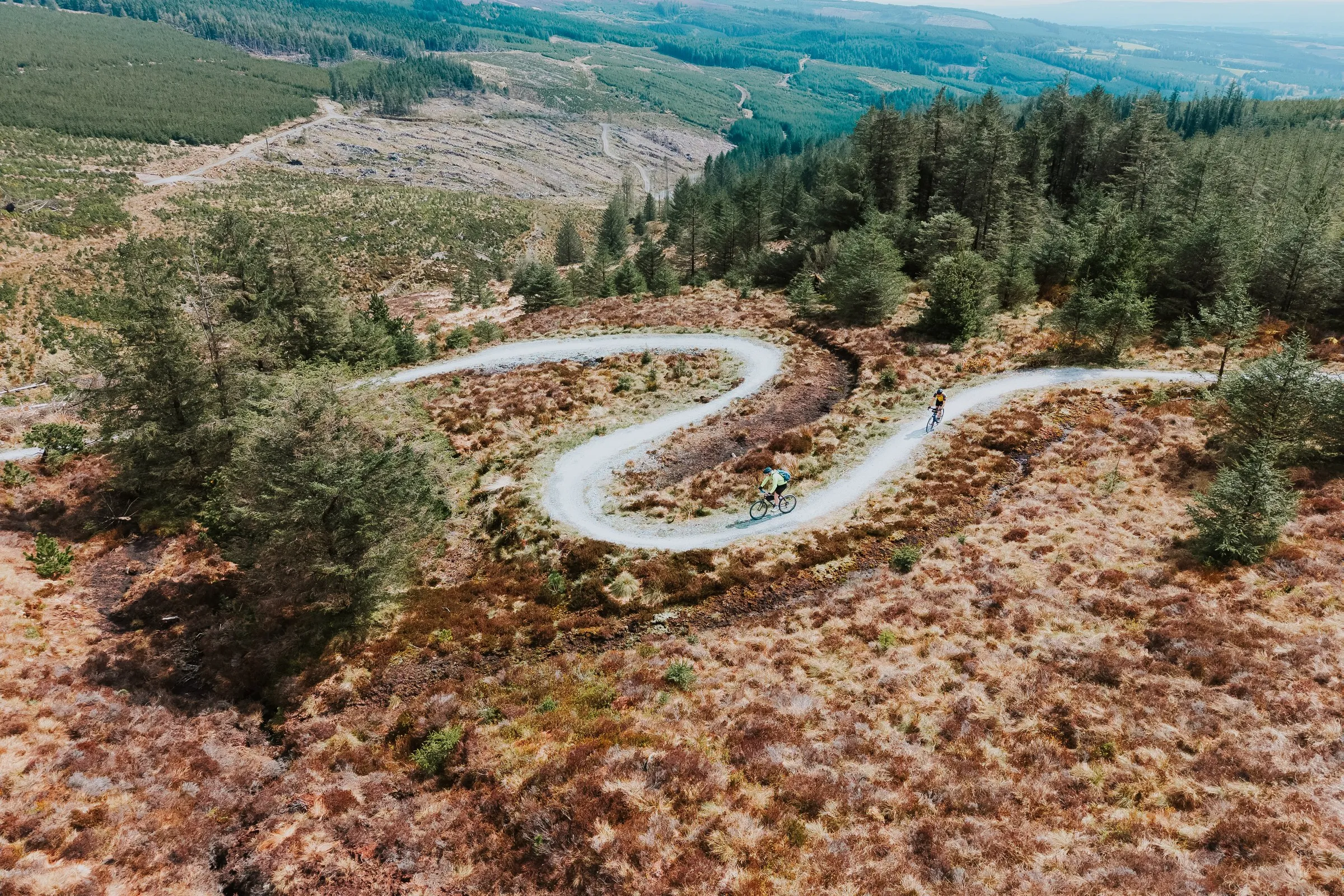 Aerial view of two cyclists on a winding gravel path through a forested, hilly landscape in Slieve Bloom.